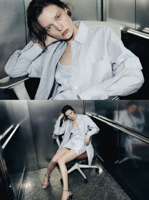A young woman with brown hair sits in a rolling chair in an elevator wearing a striped blue shirt, a dress, and strappy heels.