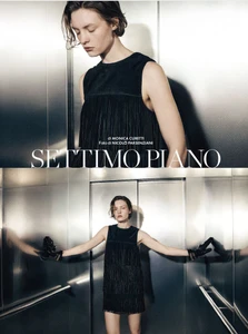 Model in a black fringed dress wearing gloves inside a metallic elevator for Settimo Piano editorial by Elle Italia.