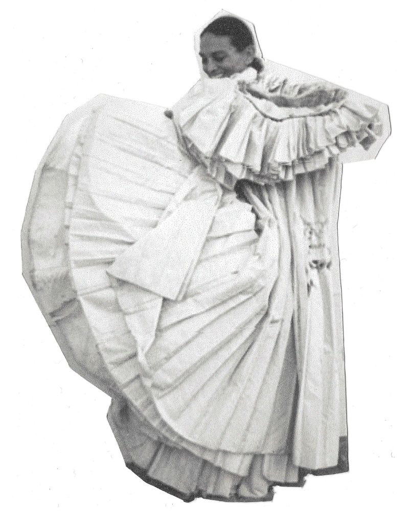 Monochrome portrait of woman in ruffled gown, sleeves, and collar, smiling slightly with eyes downcast, full shot on white backdrop.