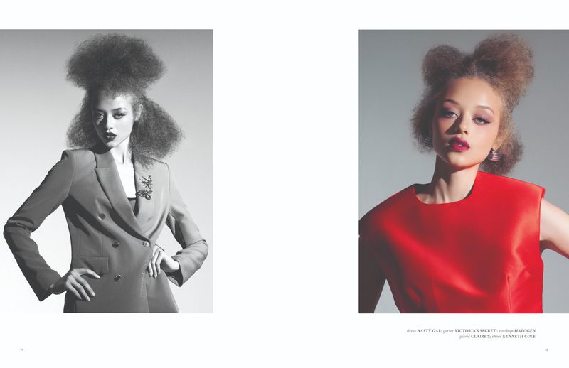 Fashion editorial of an adult female model with high-volume hair wearing a blazer, contrasted with a red top, on a plain background.