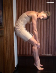 Model in a nude slip dress leaning against a wooden slatted wall, shot for Vanguard Magazine.