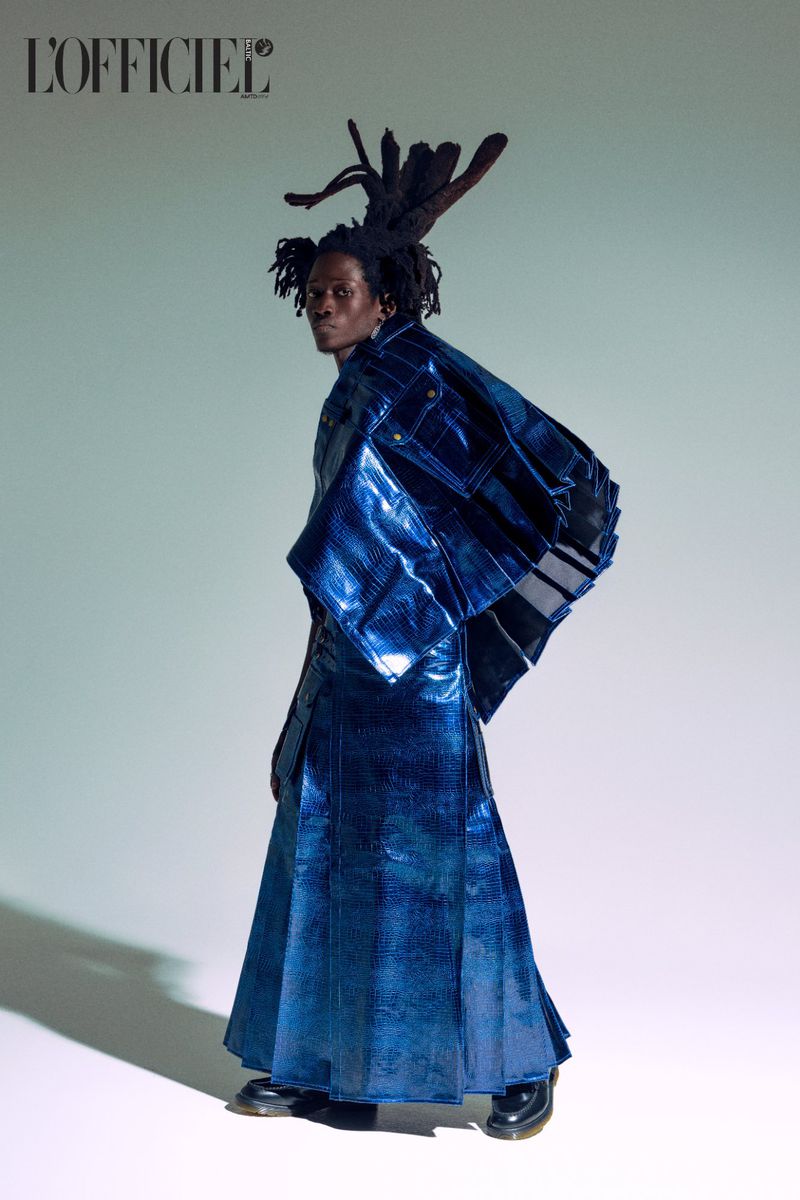 Fashionable young adult male in blue metallic coat and unique dreadlocks posing in a photo studio, editorial style, magazine cover, stylish.