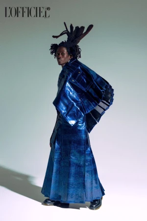 Fashionable young adult male in blue metallic coat and unique dreadlocks posing in a photo studio, editorial style, magazine cover, stylish.