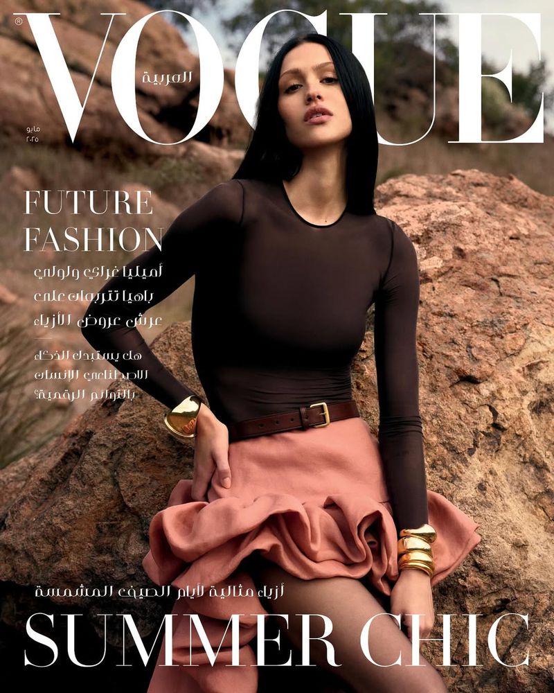 Vogue Arabia cover featuring a woman in a sheer brown top and ruffled skirt, posing against a rocky, desert-like background, fashion-editorial.