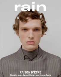 Close-up portrait of model Chandler Frye with hair clips wearing a structured grey striped high-neck top against a neutral backdrop.