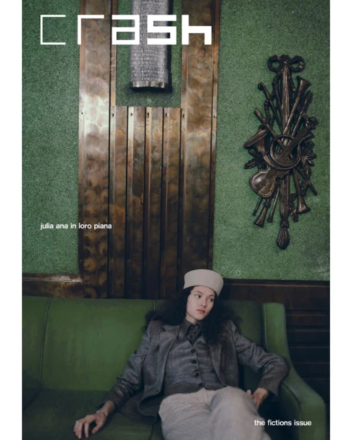 Magazine cover featuring a woman in a suit and hat sitting on a green sofa against a dark green wall decorated with metal artwork.