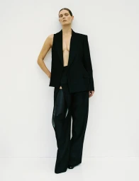 Model Malgosia Bela wearing a black sleeveless blazer and trousers against a white seamless background for Re-Edition Magazine.