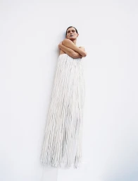 Model Malgosia Bela wearing a long white fringed dress against a plain white background for Re-Edition Magazine