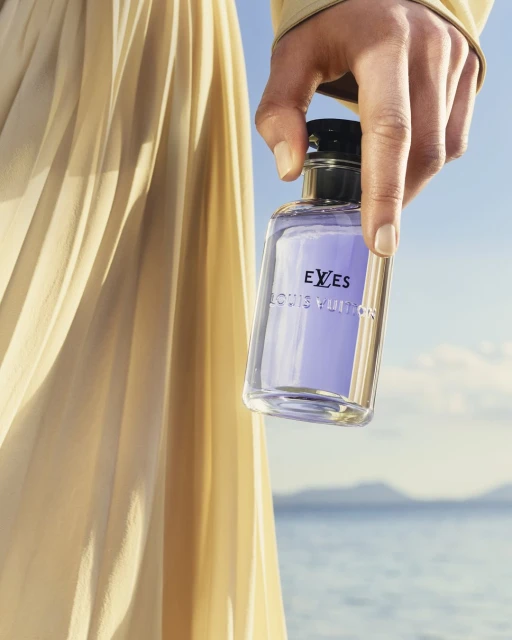 A hand holds a new Louis Vuitton fragrance bottle called Eves. The bottle is mostly clear, with the text logo visible.