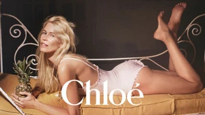 Claudia Schiffer lying prone on a yellow cushion holding a pineapple for the Chloe High Summer 2025 campaign