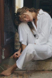 Model Natasja Madsen seated outdoors wearing a white pajama set in photography by Hadar Pitchon for Zara lingerie.