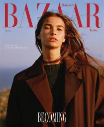 Model wearing a dark brown coat against a clear sky background for Harpers Bazaar Italia cover photography