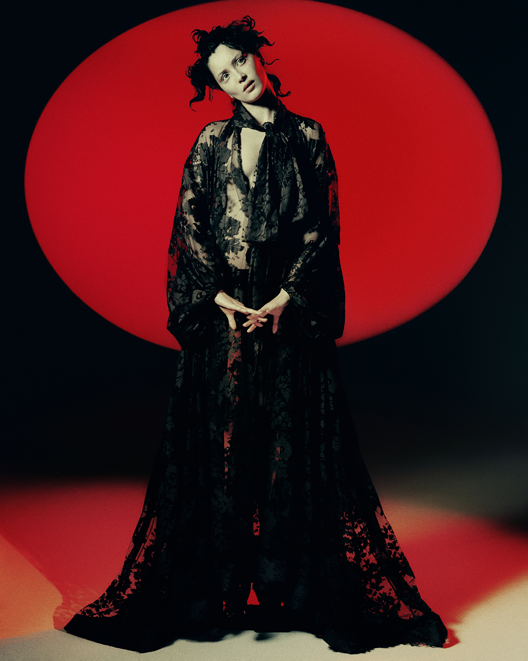 Woman in lace robe posing in front of red circle, creating a high-fashion, artistic portrait with a dramatic and elegant aesthetic.