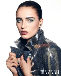 Model in a sequined jacket with dark hair slicked back against a white background for Harper's Bazaar Arabia