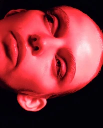 Close-up portrait of a model bathed in intense red light against a dark background for Schön Magazine