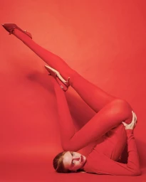 Model in red tights and heels posing against a monochromatic red background for Schön Magazine