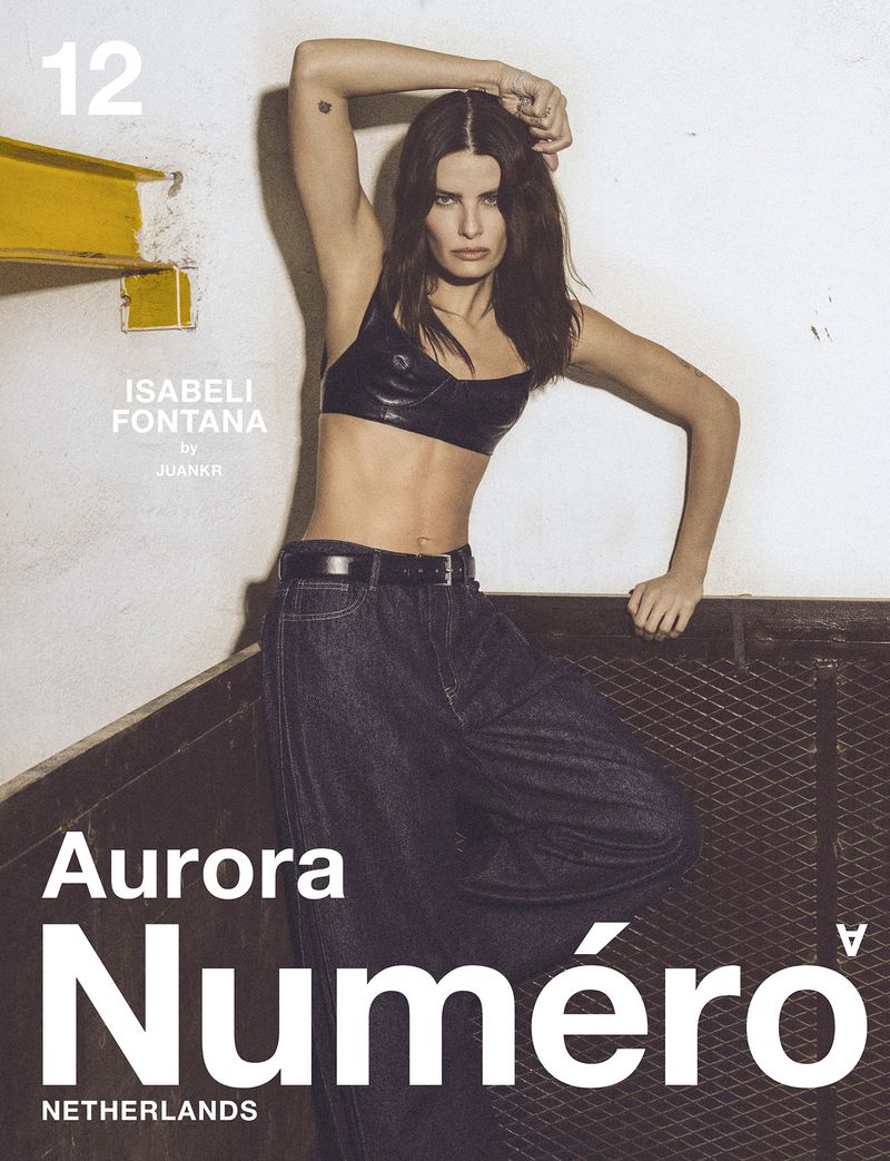 Isabeli Fontana poses in a magazine editorial shot, wearing a black crop top and loose dark denim jeans against a studio backdrop.