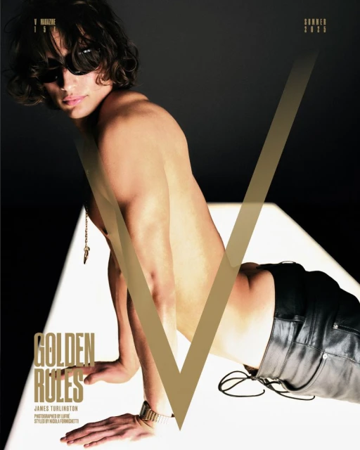 Shirtless man with sunglasses poses with V Magazine, showcasing his gold watch and necklace against a spotlighted backdrop.
