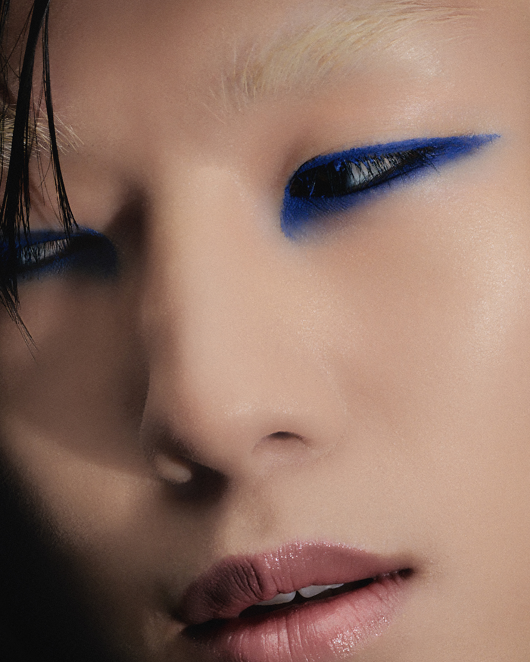 Close-up portrait of a model with bold blue eyeliner and glossy lips for an Alice.D Magazine editorial.