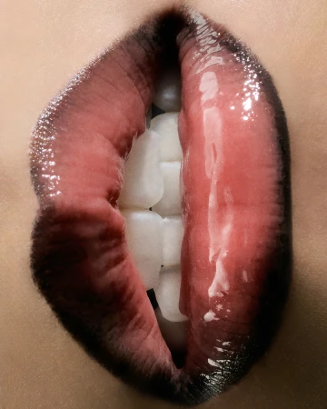 Close-up of a person's mouth with glossy lips and white teeth. The image focuses on beauty, skincare, and dental health.
