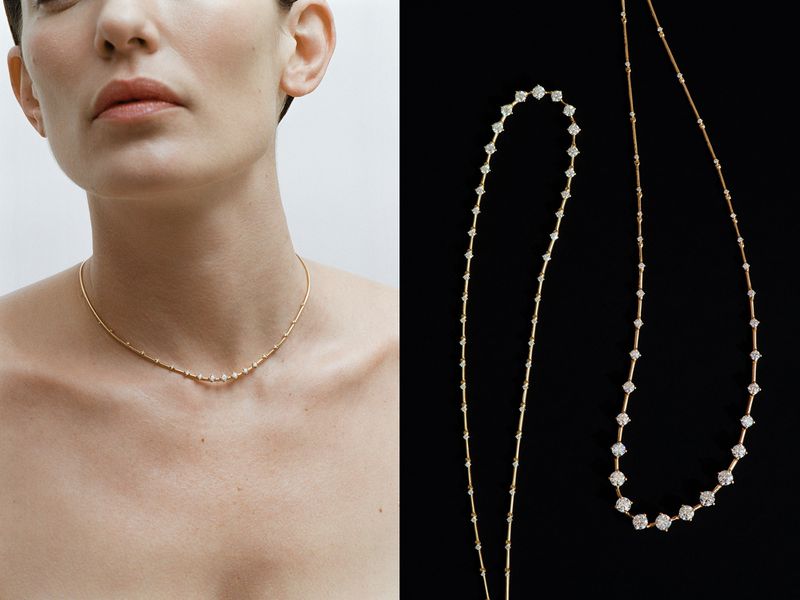 Close-up studio shot of a woman wearing a gold and diamond necklace, with another necklace displayed against a black background.
