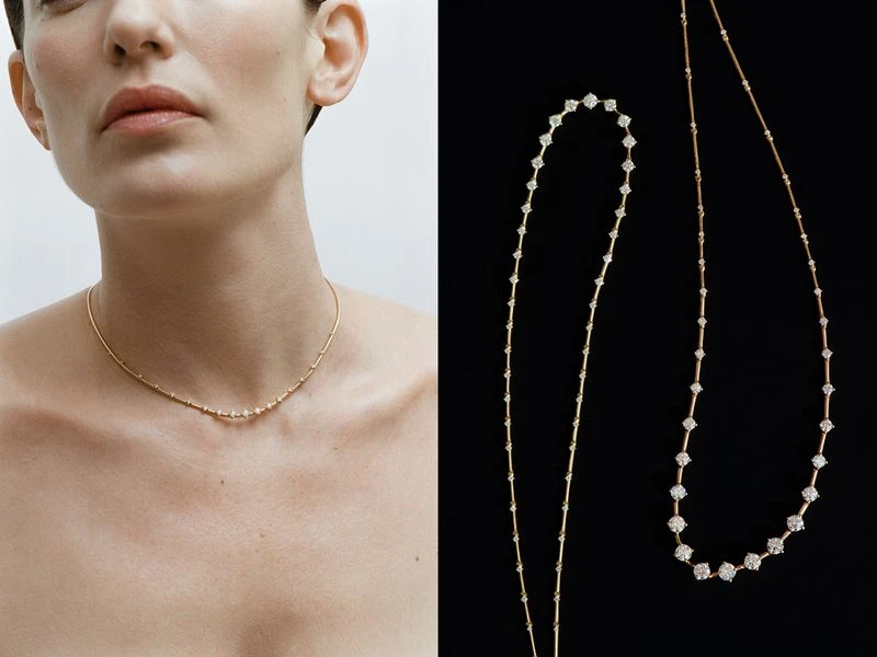 Close-up studio shot of a woman wearing a gold and diamond necklace, with another necklace displayed against a black background.