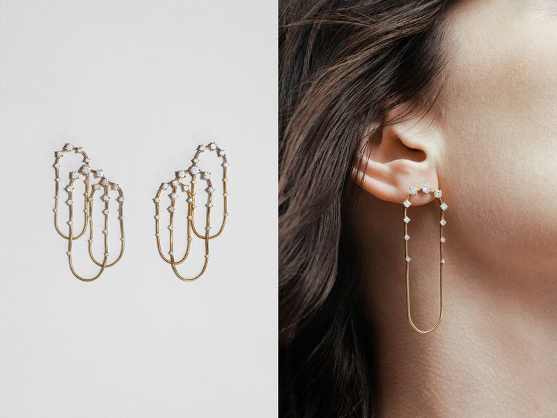 Elegant gold earrings with diamonds are displayed on a white surface and worn by a woman, showcasing jewelry design and fashion.