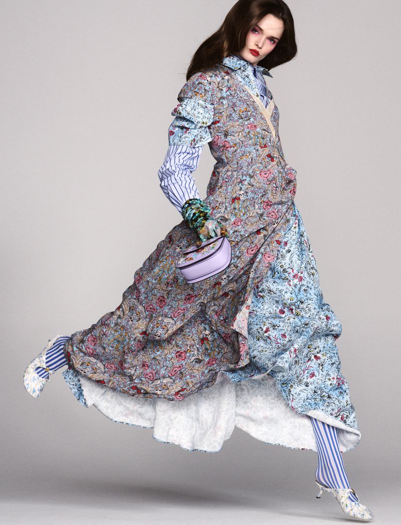 Fashion model in a floral dress strikes a pose while levitating against a neutral background, showcasing vibrant colors and unique textures.