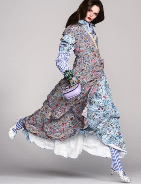 Fashion model in a floral dress strikes a pose while levitating against a neutral background, showcasing vibrant colors and unique textures.