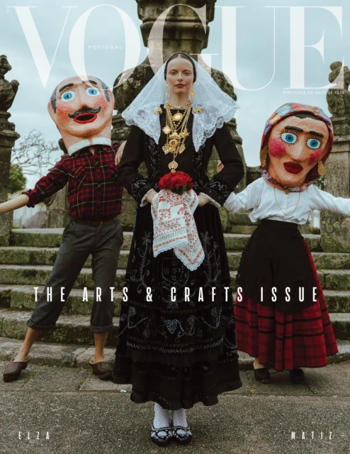 Vogue Portugal cover: A woman in traditional dress stands between two figures with oversized masks, showcasing arts and crafts.