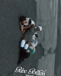 Three models lying together on an asphalt pavement in a high-angle overhead fashion editorial shot for Gabe Gordon SS25.