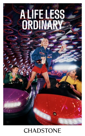Three people ride bumper cars in an amusement park under mirrored ceiling art installation, enjoying a playful moment in a brightly lit space.
