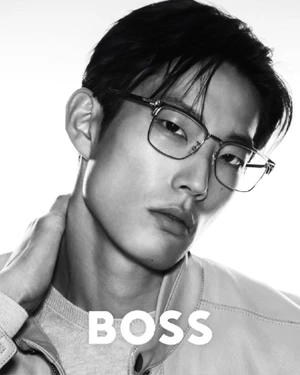 Close-up monochrome portrait of a model wearing optical glasses and a jacket for the BOSS 2025 Eyewear Campaign against a white background.