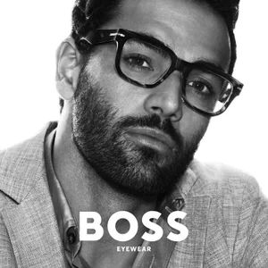 Matteo Berrettini wearing black eyeglasses and a grey blazer in a high contrast black and white portrait for BOSS Eyewear