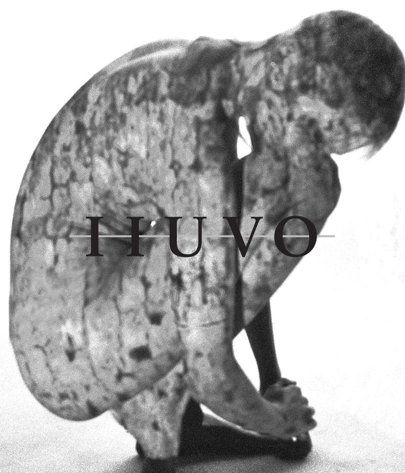 Monochrome image of an adult crouched with head down and hands clasped, displaying a pattern resembling tree bark on the body. Text 'IUVU'.
