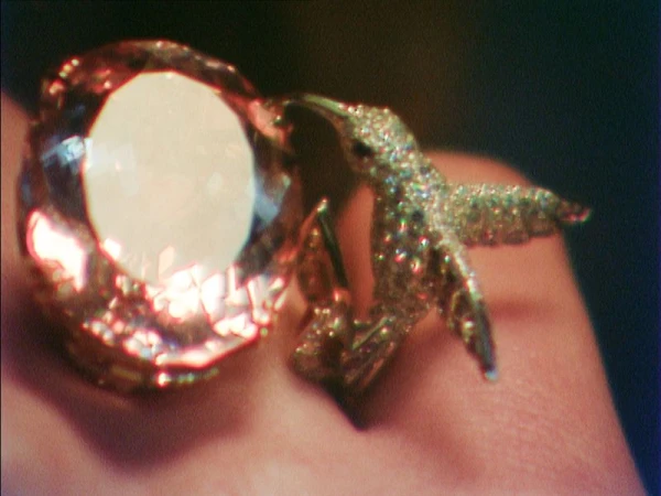 Close-up of a sparkling bird-shaped ring with a large gemstone, set against a dark backdrop. Jewelry design with intricate details.