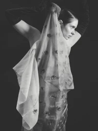 Black and white portrait of actress Daphne Patakia wearing sheer embroidered fabric and long black gloves for Crash Magazine