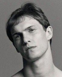 Close-up portrait of a male model with textured hair against a neutral grey background for Double Magazine.