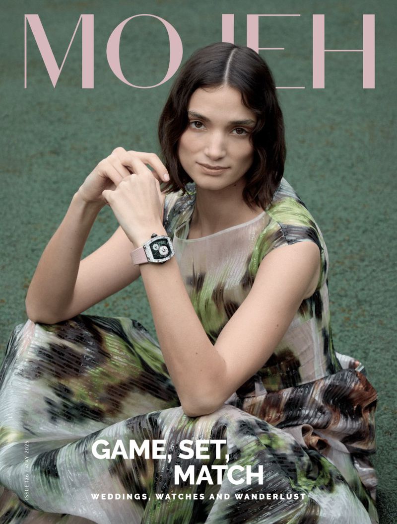 Magazine cover featuring a woman with dark hair and a patterned dress sitting outdoors, wearing a wristwatch, and the masthead 'MOJEH'.