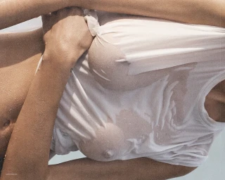 Close-up of a woman wearing a wet white t-shirt against an outdoor background