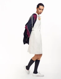Model Lara Menezes wearing a white dress and jacket draped over her shoulder in a studio for Re-Edition Magazine