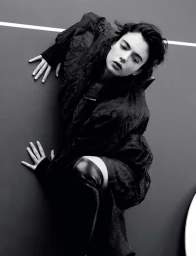 Deva Cassel in a dark textured jacket and thigh-high leather boots against a grey studio wall for Re-Edition Magazine