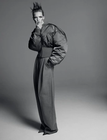 A monochrome fashion shot featuring a model in a puffy bomber jacket and wide-leg trousers against a grey backdrop, showcasing edgy style.