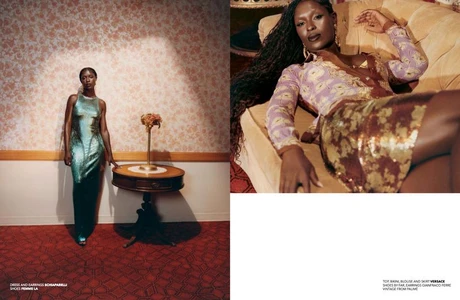 Jodie Turner-Smith standing beside a round wooden table in a vintage interior with patterned wallpaper