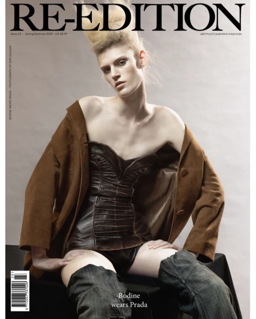 Magazine cover featuring a single fashion model with stylized blonde hair wearing a brown jacket and a black corset. The model is sitting.