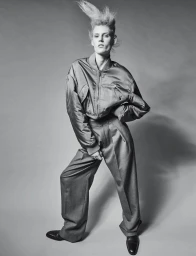 Model Bodine Van Galen in a bomber jacket and trousers with spiked hair against a grey background for Re-Edition Magazine