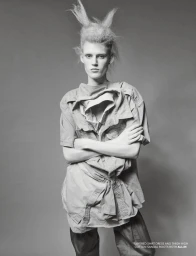 Model Bodine Van Galen with spiky hair and layered shirt dress against grey background for Re-Edition Magazine Bodine project