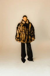 Model wearing a voluminous textured patterned coat and black trousers against a neutral background for Double Magazine.