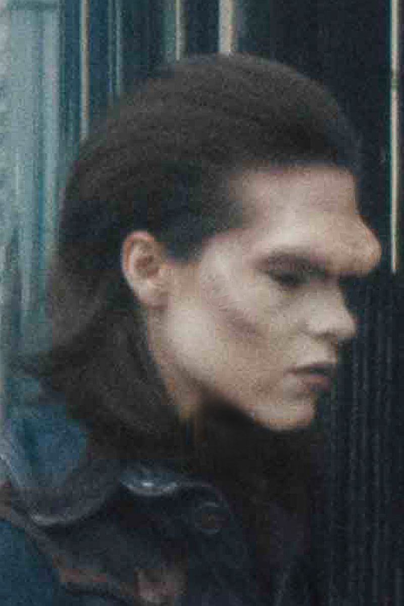 Profile shot of a person with a unique facial feature against a muted background, showcasing texture and muted color palette.