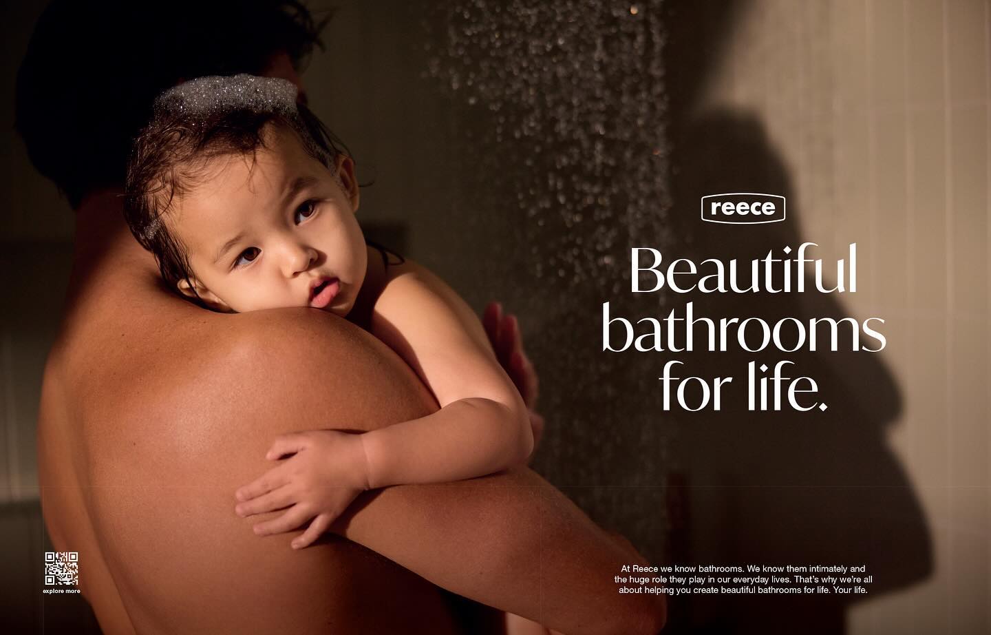 Father holding his baby girl in the bathroom near the shower. Bathroom advertising photography for Reeces with the text 'Beautiful bathrooms for life'.